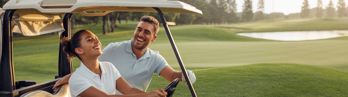 Smiling couple in a golf cart on a picturesque course